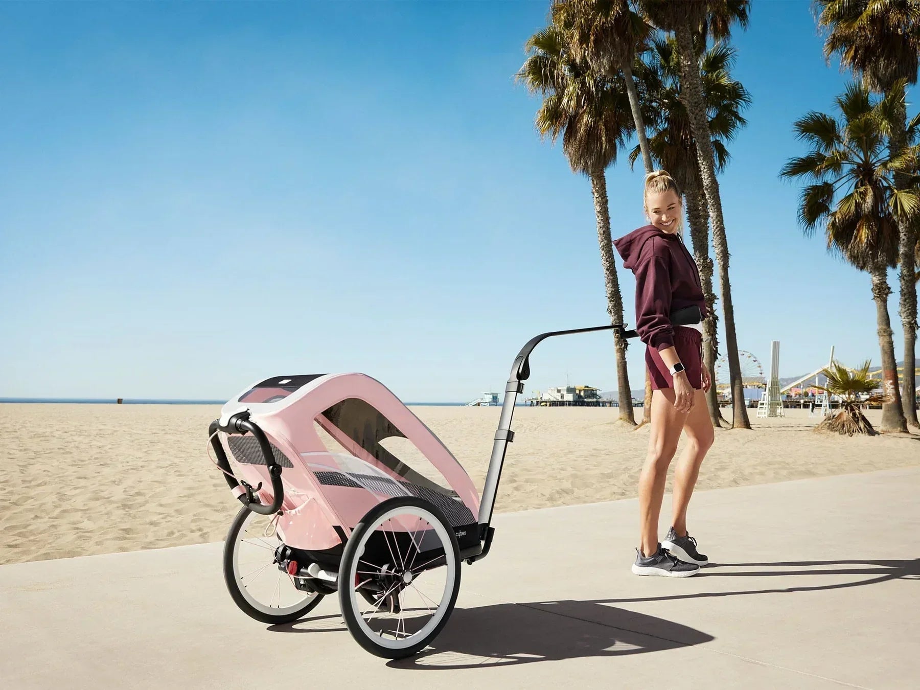 Cybex Zeno multisport running stroller with hands-free kit on a sunny beach path.